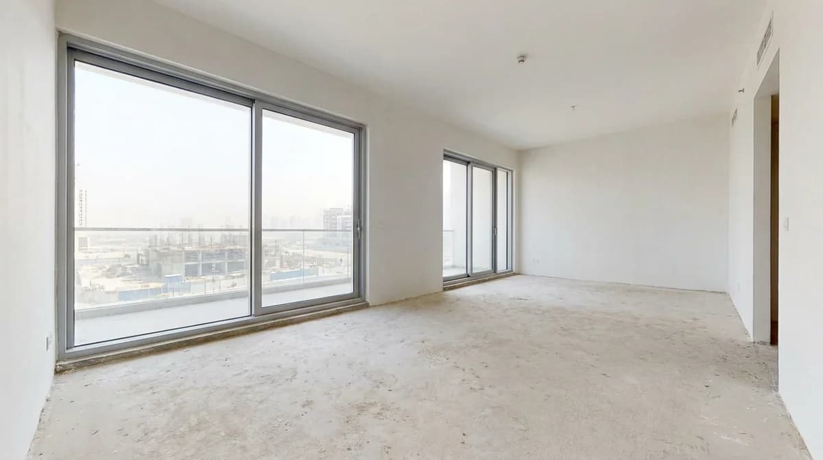 Leere, unmöblierte Neubauwohnung mit kahlem Boden und raumhohen Fenstern
