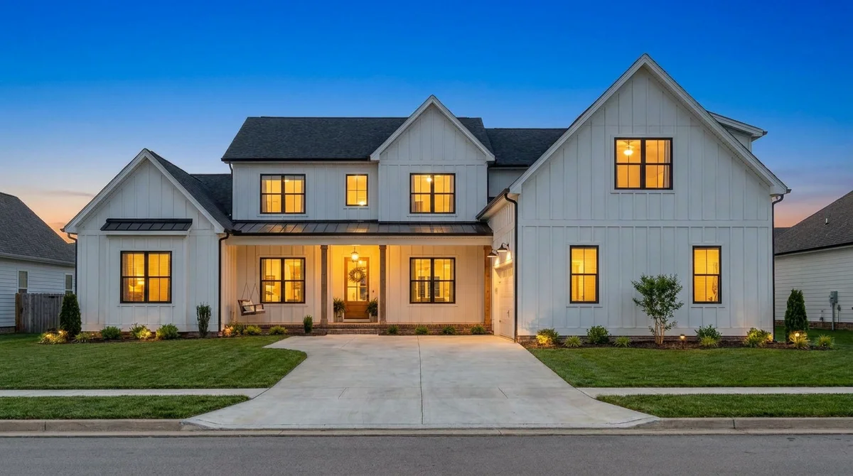The same modern farmhouse exterior converted to virtual twilight with warm interior lights and a deep blue sky